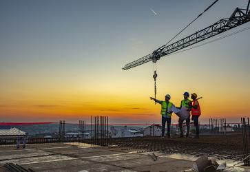 Multi ethic workers talking at construction site reviewing plans